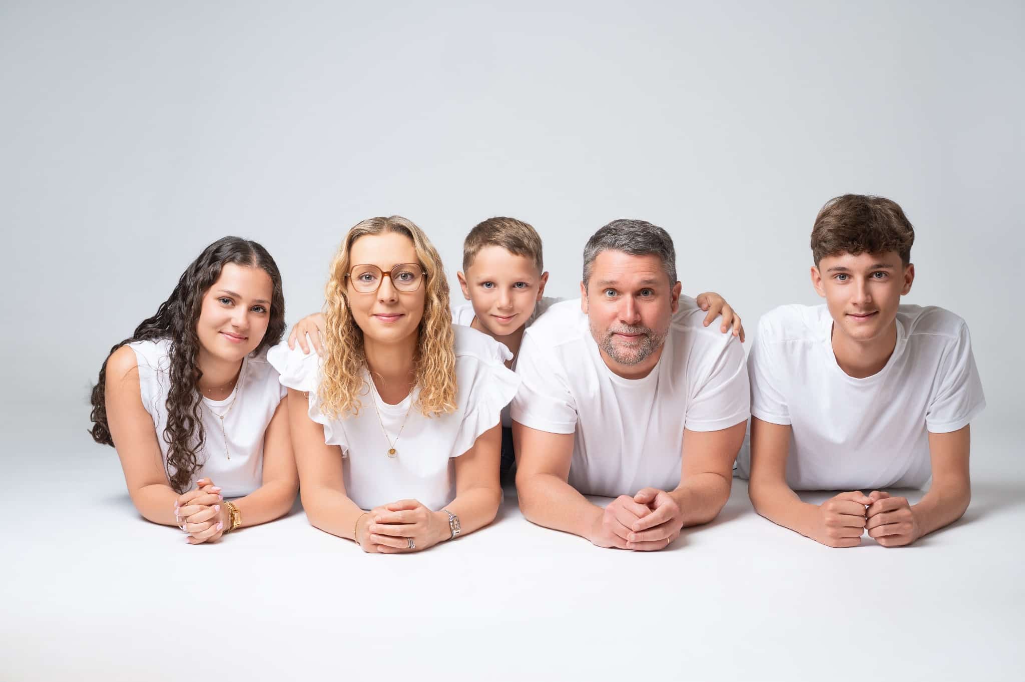 Une famille de cinq personnes allongées côte à côte au studio